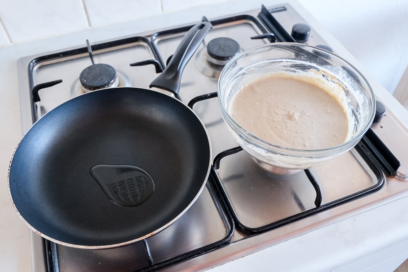 frying pan with oil and batter bowl on stove vegan buckwheat banana pancakes