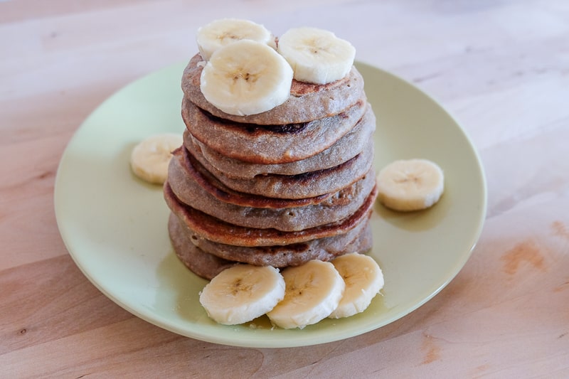 vegan buckwheat banana pancakes in stack on plate with banana slices