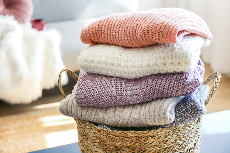 basket full of cozy knitted sweaters on room