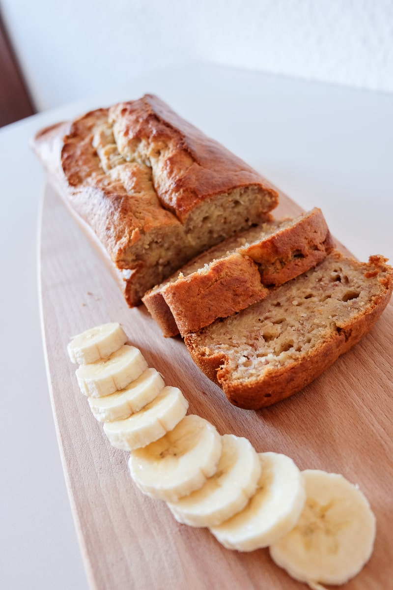 easy banana bread on wooden cutting board with sliced bananas