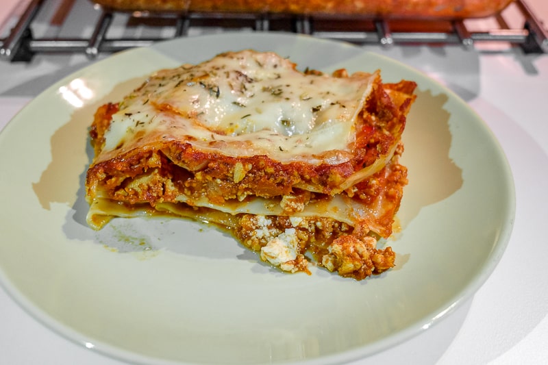 slice of layered vegetarian lasagna on green plate on table