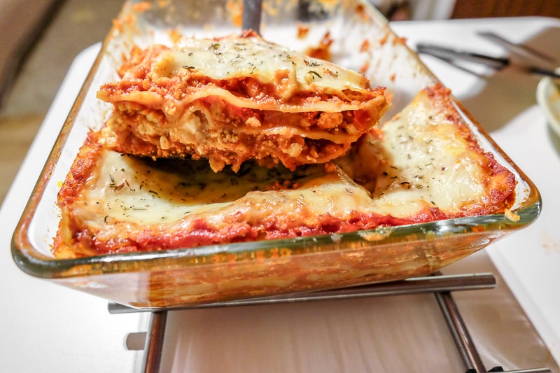 lasagna slice lifted from pan over table