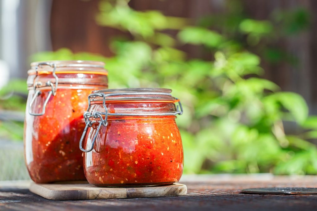 clear jars of red tomato paste outside how to reduce food waste at home